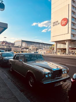 A vintage Bentley parked in Berlin with cityscape and Bikini Berlin mall in the background.