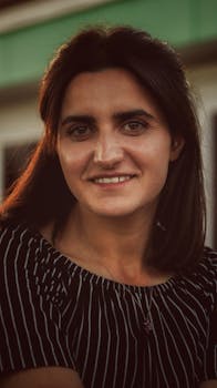 Close-up portrait of a brunette woman with a warm smile, captured at sunset.