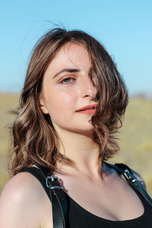 Free Close-up portrait of a young woman with a warm smile outdoors in sunlight. Stock Photo