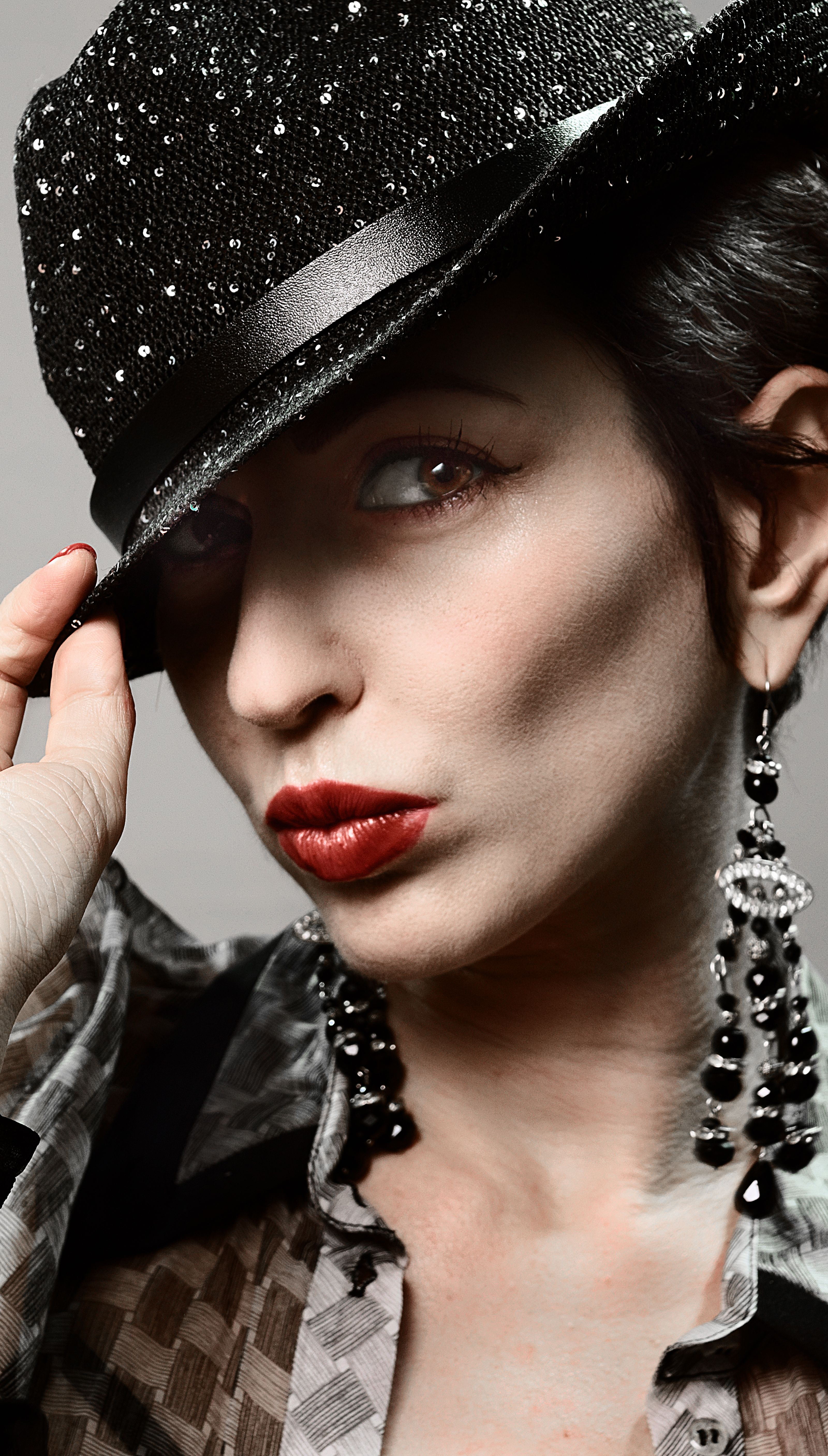 Retrato de moda de uma jovem com lábios vermelhos e chapéu brilhante, exibindo elegância.