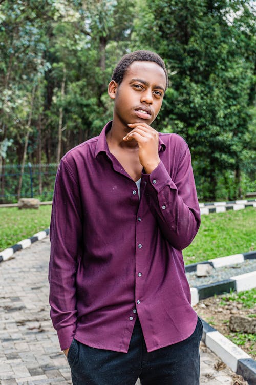 Young Man in Purple Shirt Posing in a Park