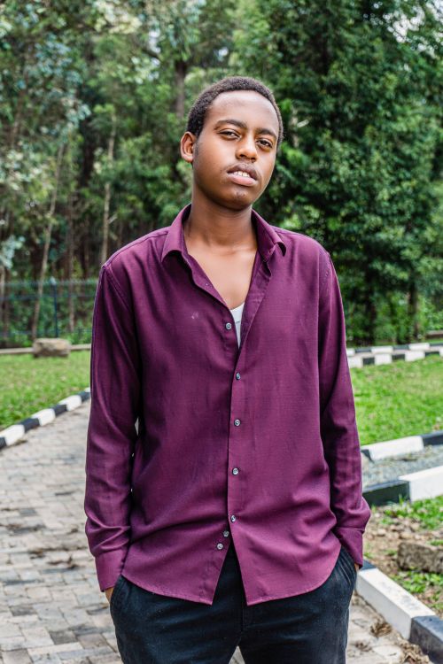 Free Fashionable young man in a purple shirt posing outdoors in a peaceful park setting. Stock Photo