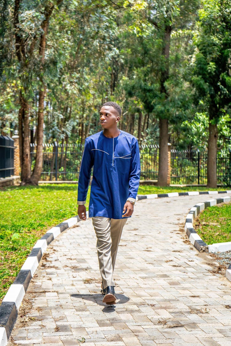 Young Man In Blue Shirt Walking In A Park