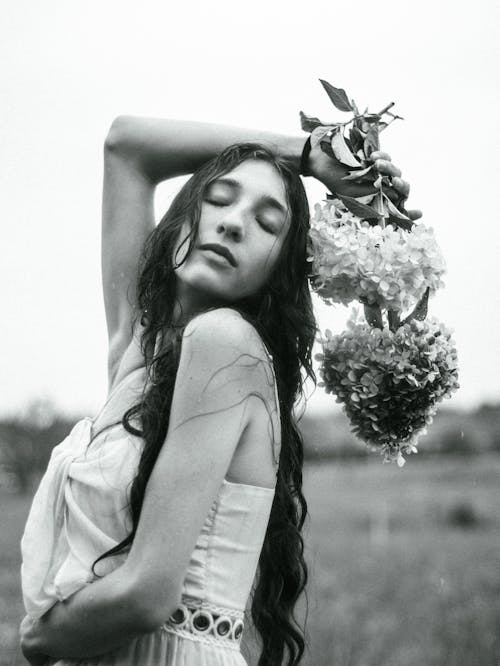 Black and White Photo of a Woman Posing with Hydrangea Flowers in a Field