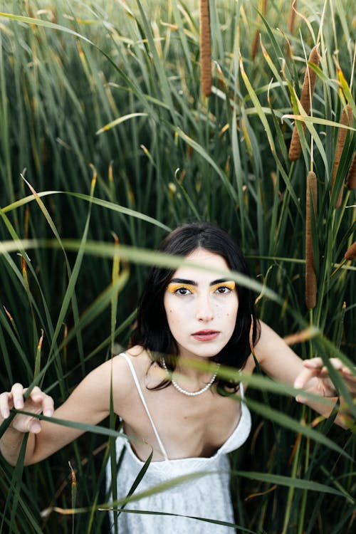 Young Woman in a White Dress Standing on a Field with High Grass