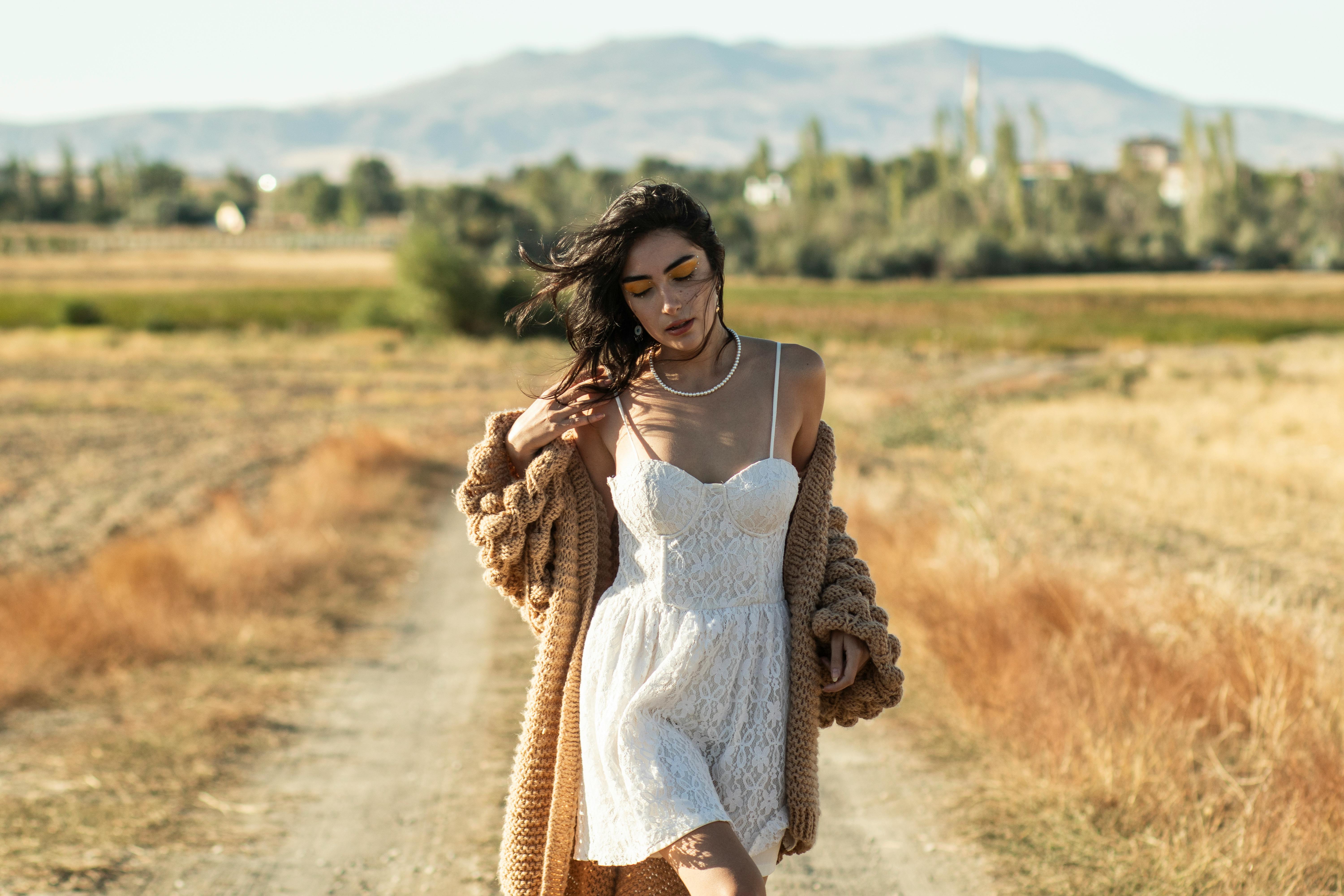 Fashionable woman posing on a path in a summer field, exuding style and elegance.