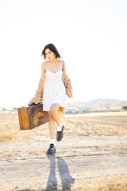 Woman in Summer White Dress Carrying Suitcase