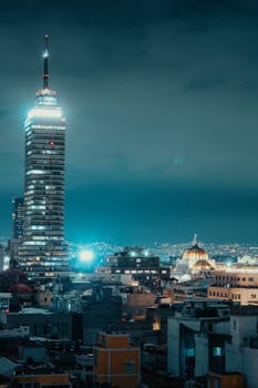 Stunning nighttime view of the Mexico City skyline featuring Torre Latinoamericana illuminated against the blue sky.