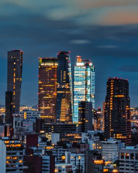 Vibrant cityscape of Mexico City featuring modern skyscrapers illuminated at dusk.