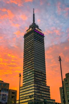 Modern skyscraper set against a dramatic sunset sky in Mexico City.