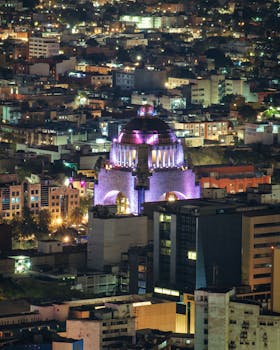 A stunning aerial view of the illuminated Monument to the Revolution in Mexico City at night.