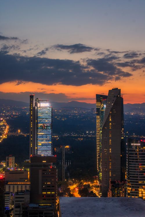 Free A breathtaking view of Mexico City's modern skyline illuminated at sunset with skyscrapers and vibrant colors. Stock Photo