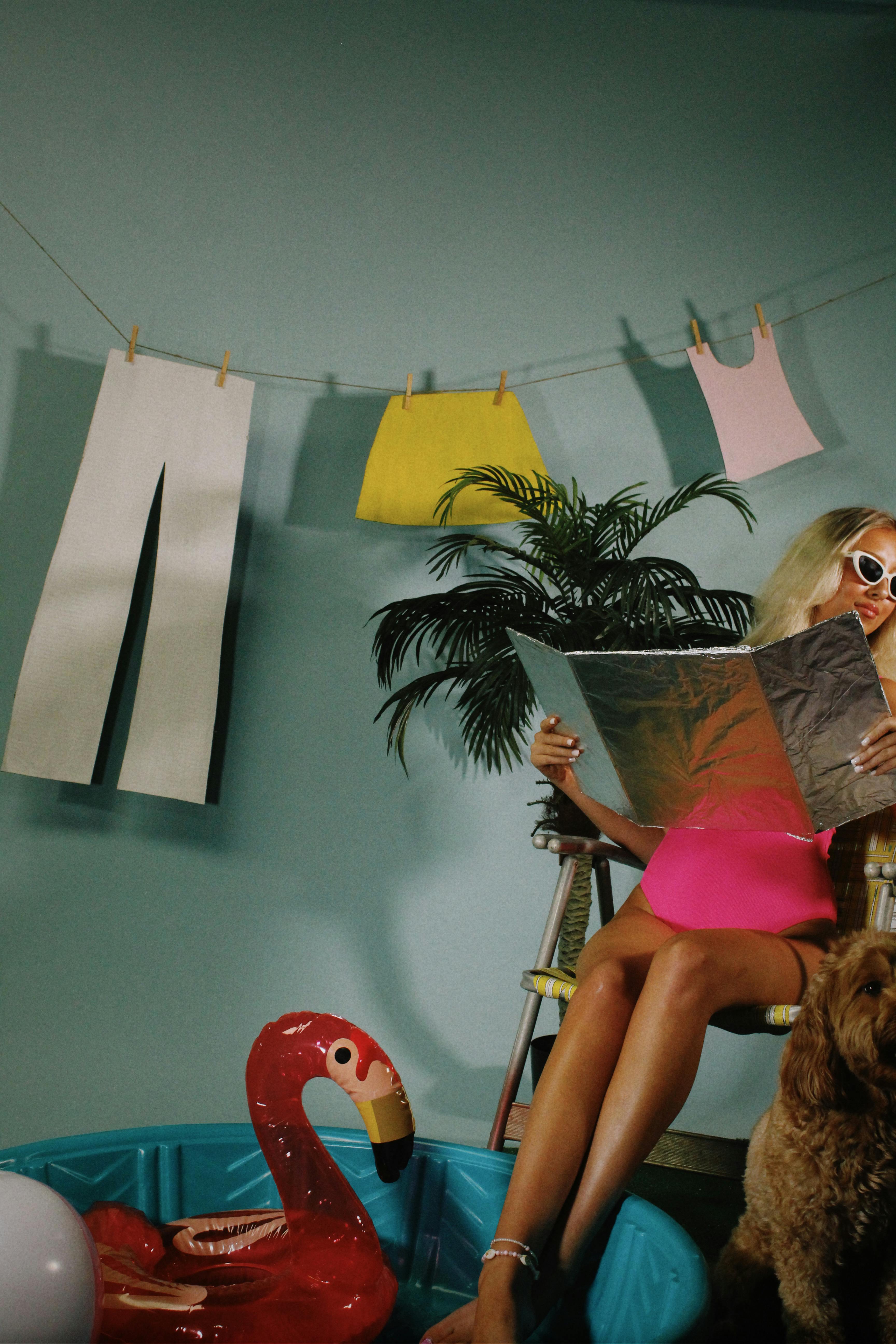 Trendy woman in vibrant setting reading a magazine with playful summer decor.