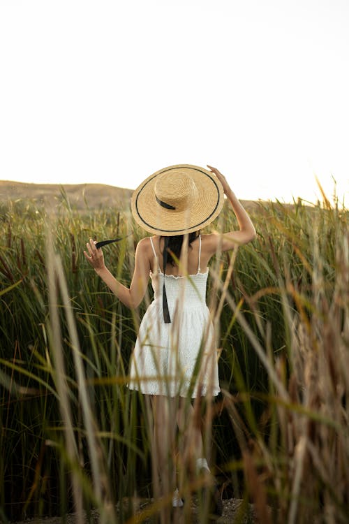Free A Woman in a White Dress Standing on a Grass Field Stock Photo