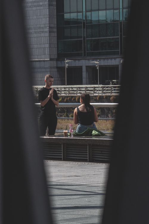 Free A casual interaction between a man and woman enjoying a sunny cityscape view. Stock Photo
