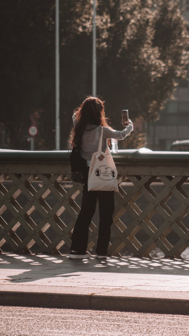 Woman Taking A Picture On A Bridge