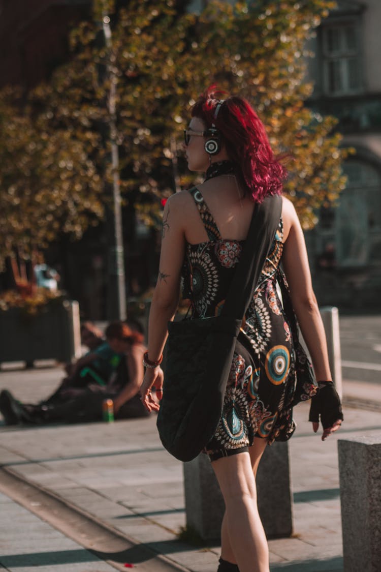 Red Headed Woman With Headphones Walking On A City Street