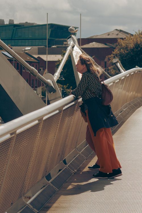 Free Urban scene of a woman standing on a city bridge in daylight, capturing modern city life. Stock Photo