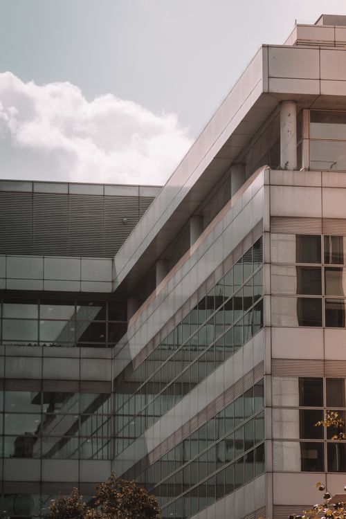 Free A sleek modern building featuring a reflective glass facade against a clear sky. Stock Photo