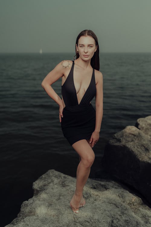 A woman in a black dress posing on a rock