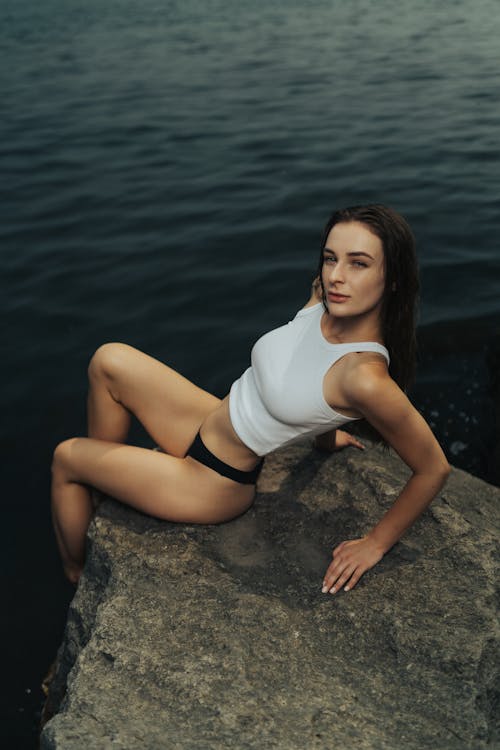 A woman in a white top sitting on a rock