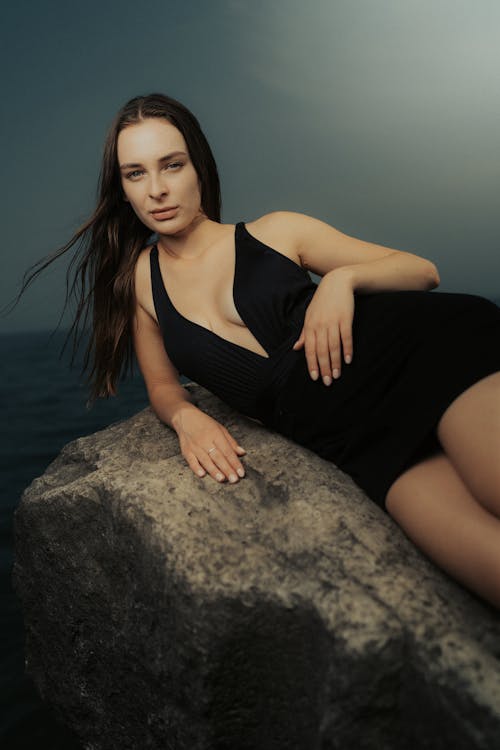 A woman in a black dress sitting on a rock