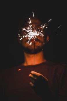 A man illuminates the night with a sparkler, creating a warm, festive glow.