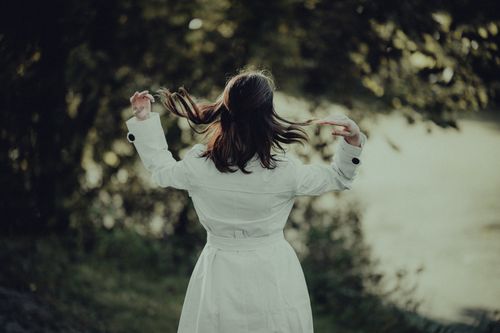 Free Woman in a white trench coat enjoying a serene autumn day in a park setting. Stock Photo