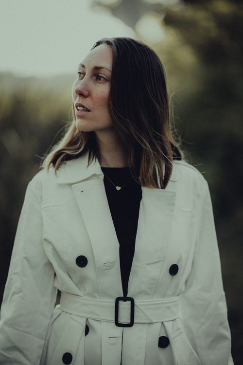 Free Stylish woman posing outdoors in a white trench coat during fall. Stock Photo