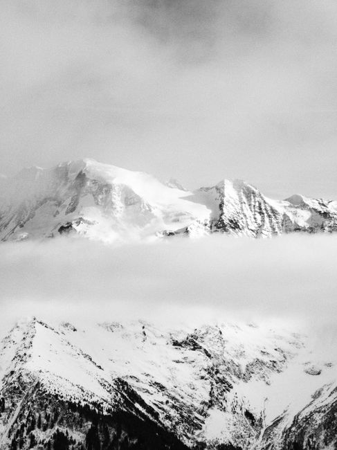 Stunning monochrome view of snow-covered mountain peaks shrouded in mist.
