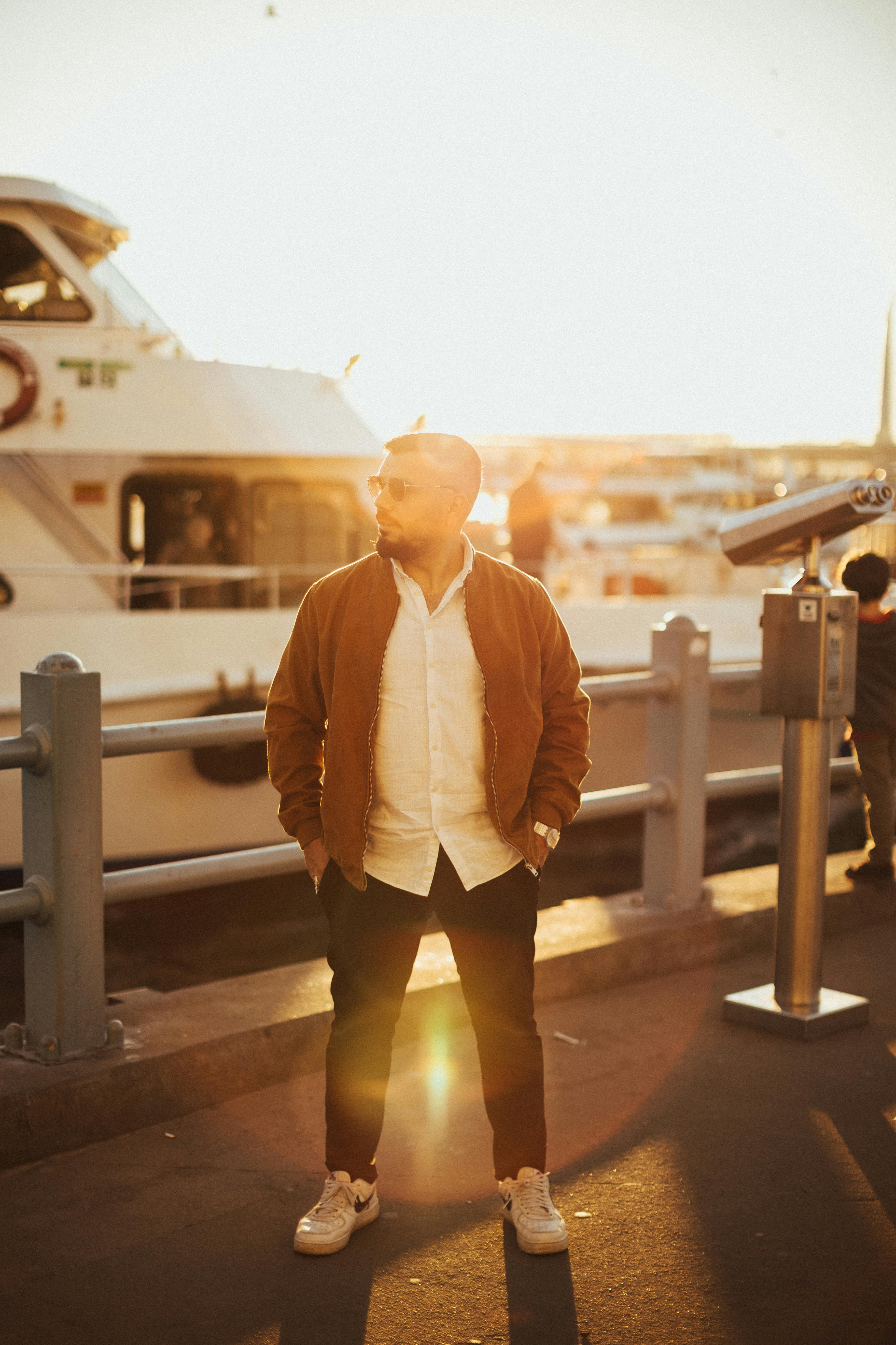 a man standing in front of a boat in the sun