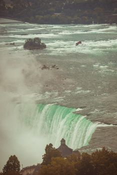 Breathtaking aerial view of Niagara Falls flowing powerfully amidst lush surroundings.