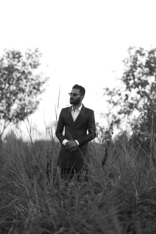 Free Stylish man in sunglasses wearing a suit standing in a meadow, black and white portrait. Stock Photo