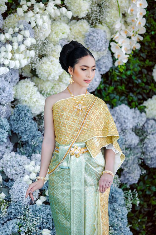Free A woman in traditional clothing stands gracefully against a floral background, exuding elegance and beauty. Stock Photo