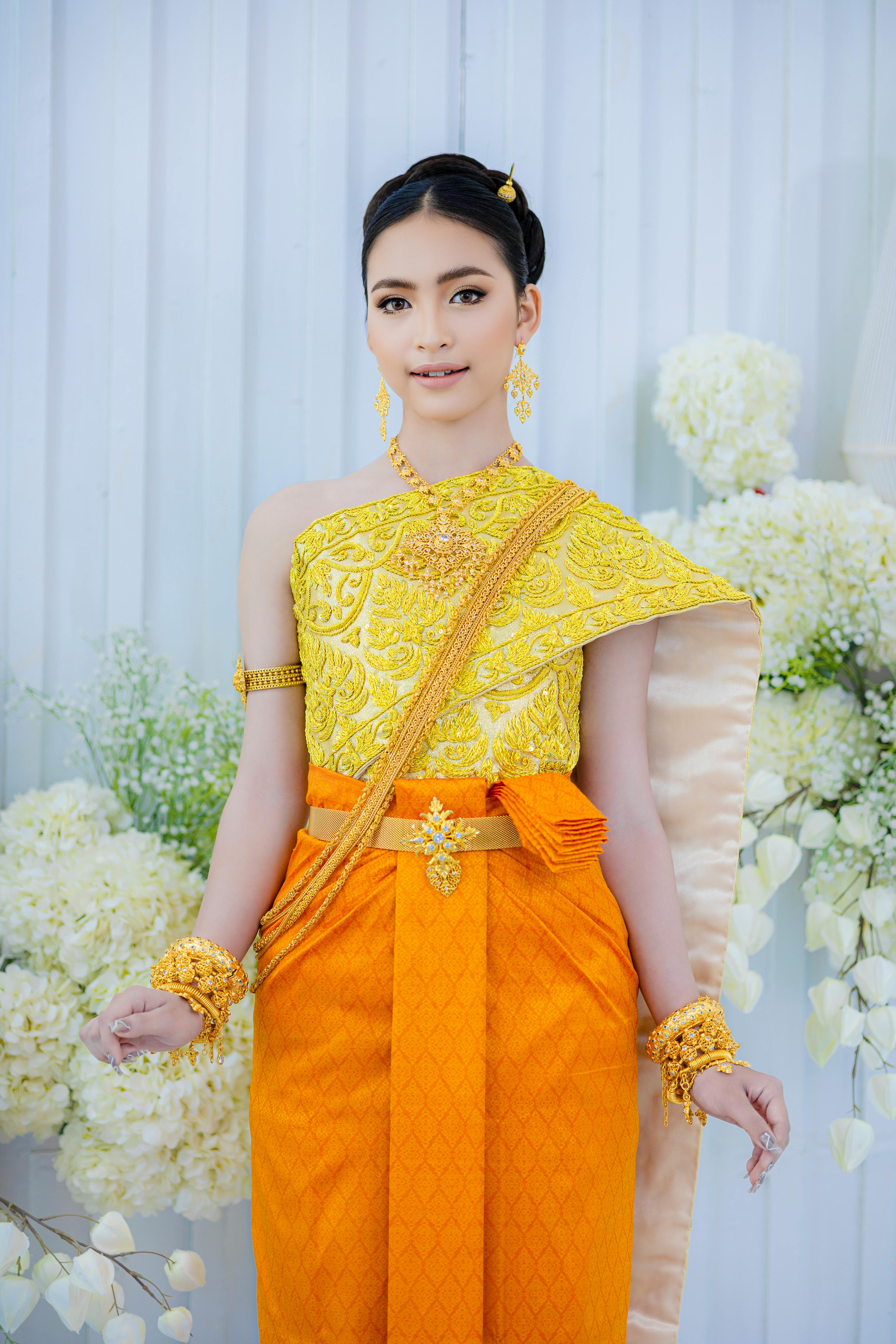 Young woman in traditional Khmer wedding attire, smiling with elegant jewelry.