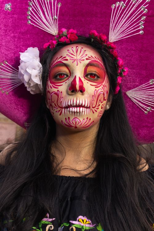 Free Close-up portrait of a woman with Day of the Dead face paint wearing a pink sombrero. Stock Photo
