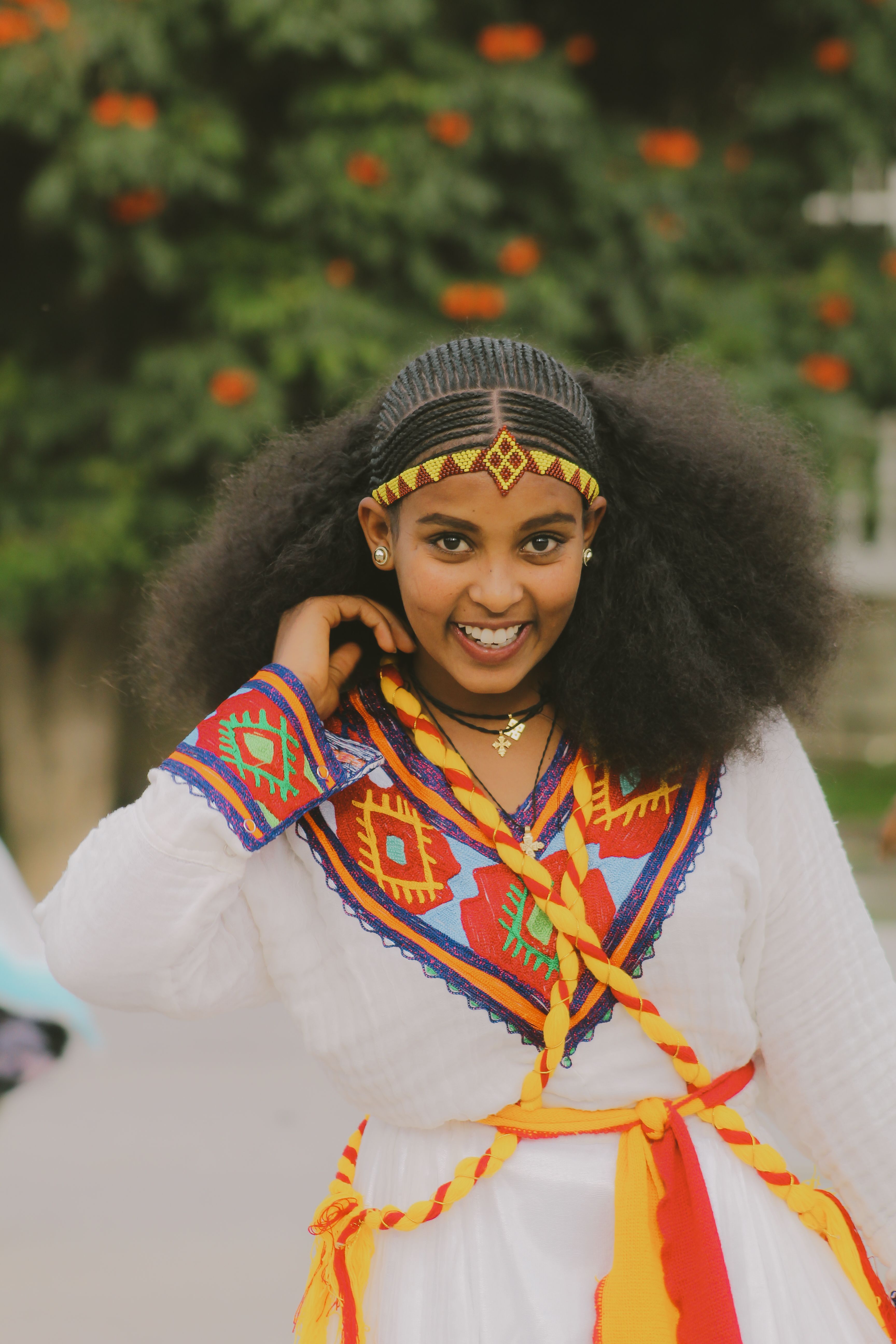 A young woman confidently poses outdoors in vibrant traditional attire, expressing joy and culture.