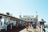 在阳光明媚的日子里，标志性的布莱顿码头熙熙攘攘，游客们享受着海滨长廊