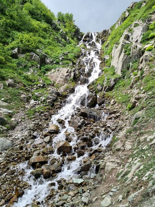 Free Stunning waterfall cascading down a rugged mountainside, surrounded by lush greenery. Stock Photo