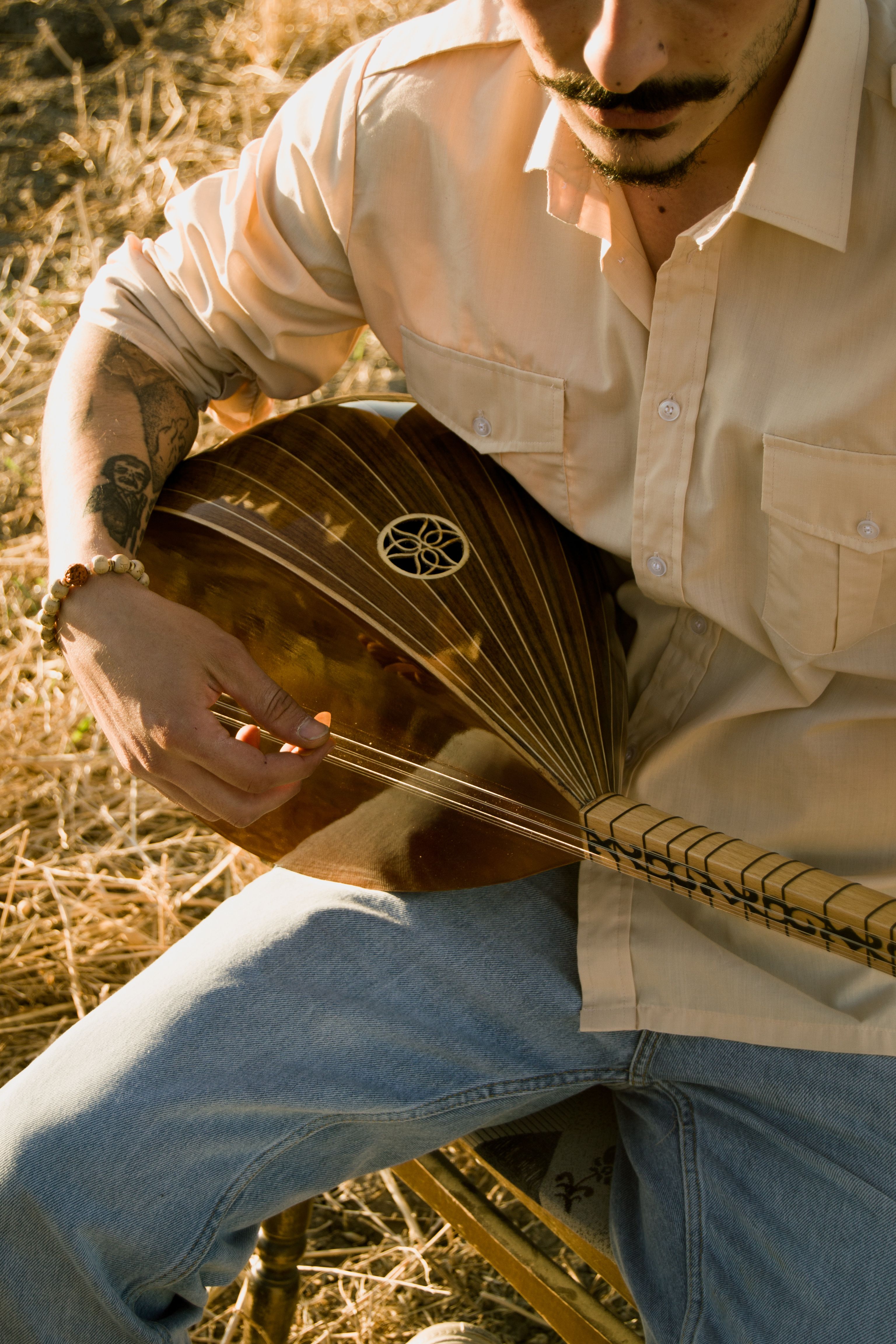 A man plays the oud outdoors, capturing the essence of traditional music with a modern touch.