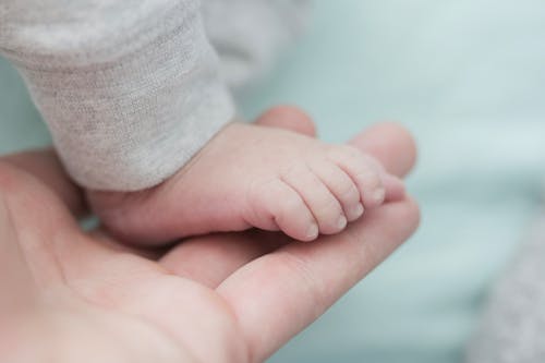 Baby Met Grijze Bodems Op De Hand Van De Persoon