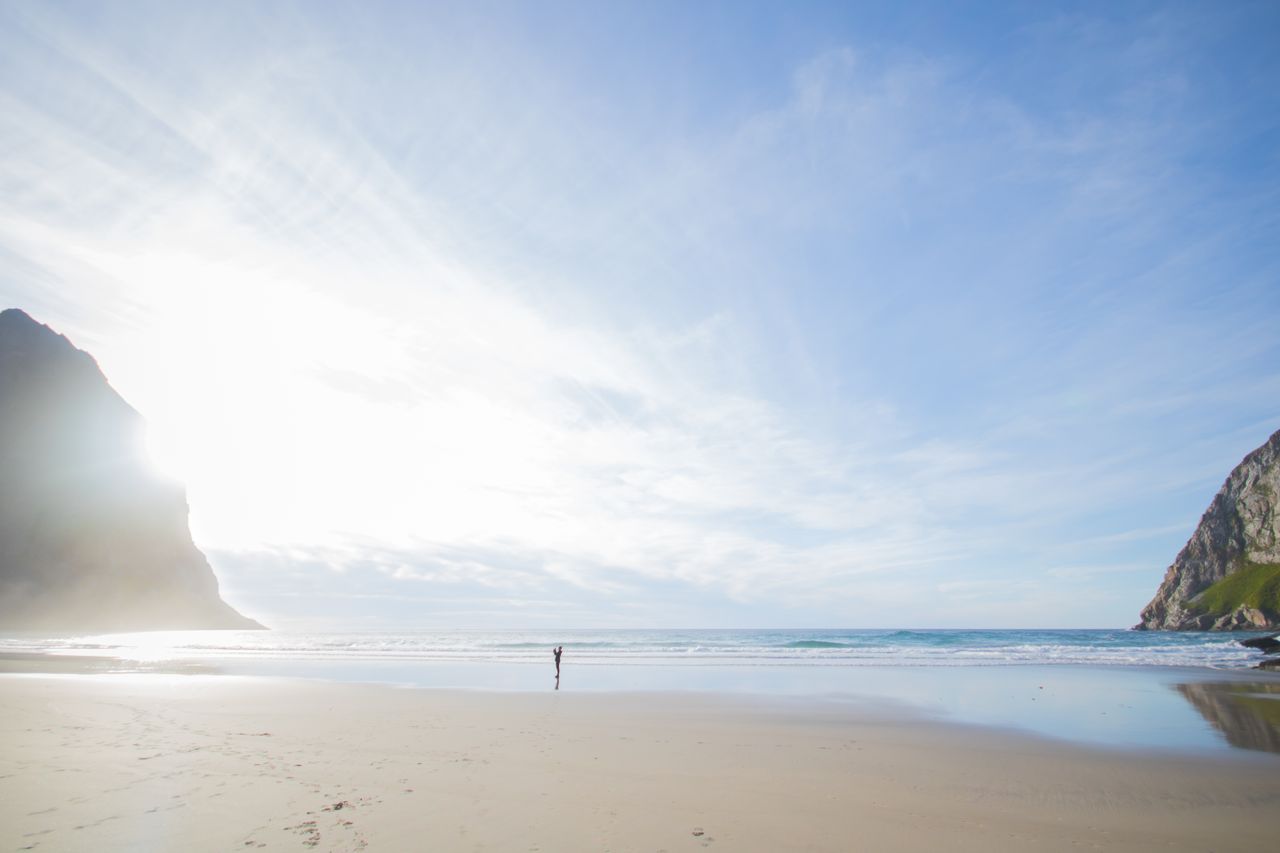 a peaceful beach scene with towering cliffs blue sky and gentle waves
