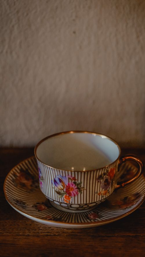 Free A beautifully detailed hand-painted porcelain cup and saucer on a wooden surface. Stock Photo