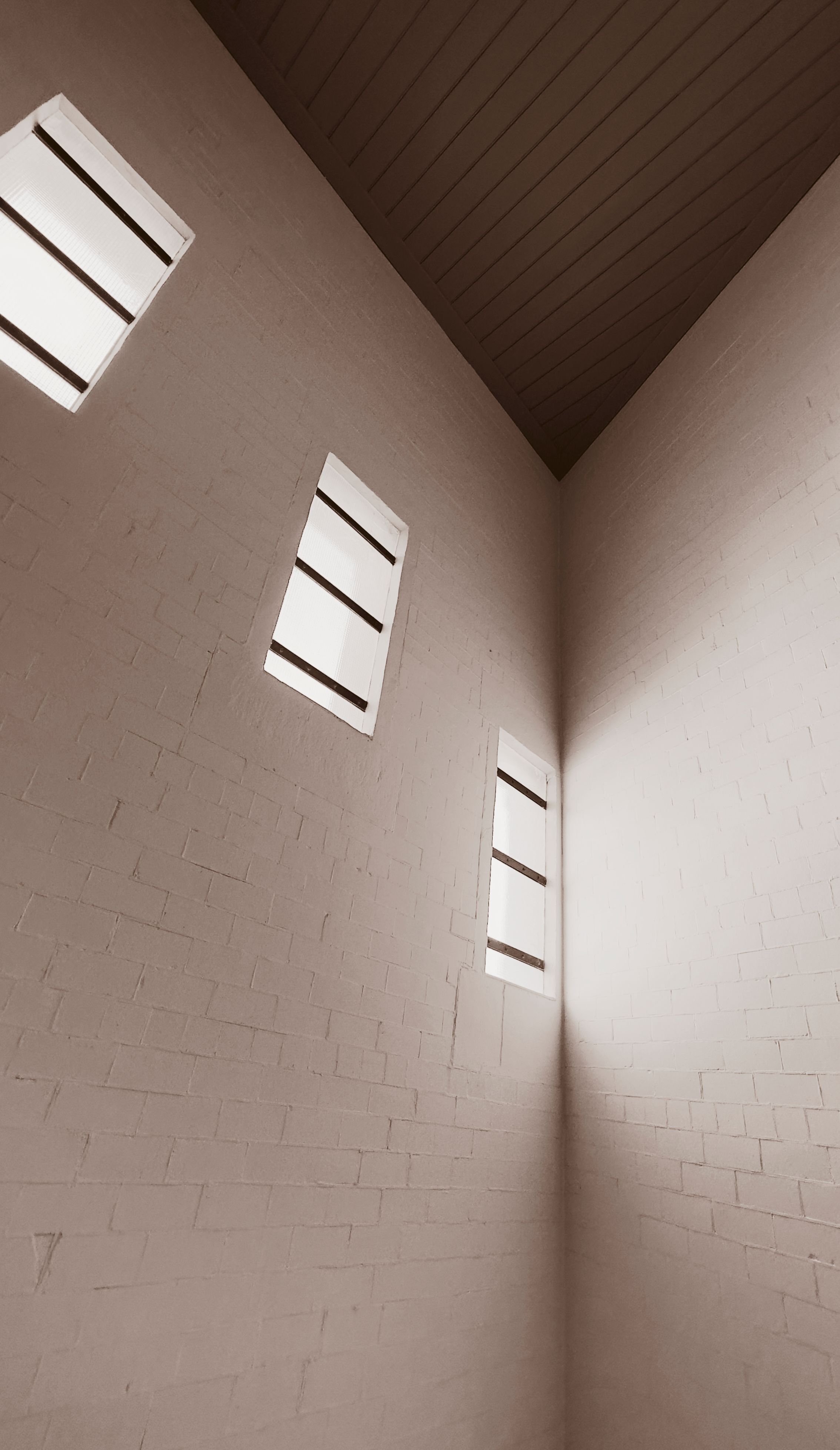 Abstract minimalist interior featuring asymmetrical windows and white brick walls creating unique light patterns.