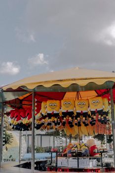 Carousel stall at a fairground displaying plush toys outdoors under a sunny sky.