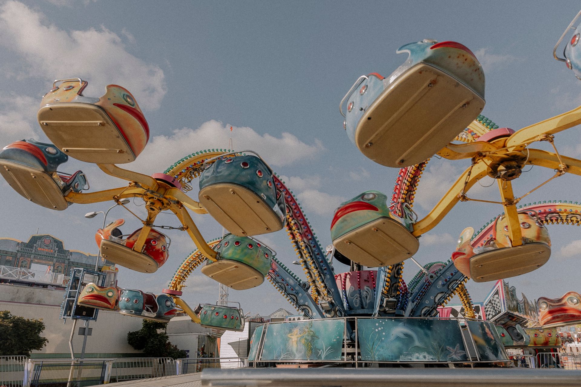 A vibrant amusement park ride featuring colorful fish-shaped seats under a clear blue sky.