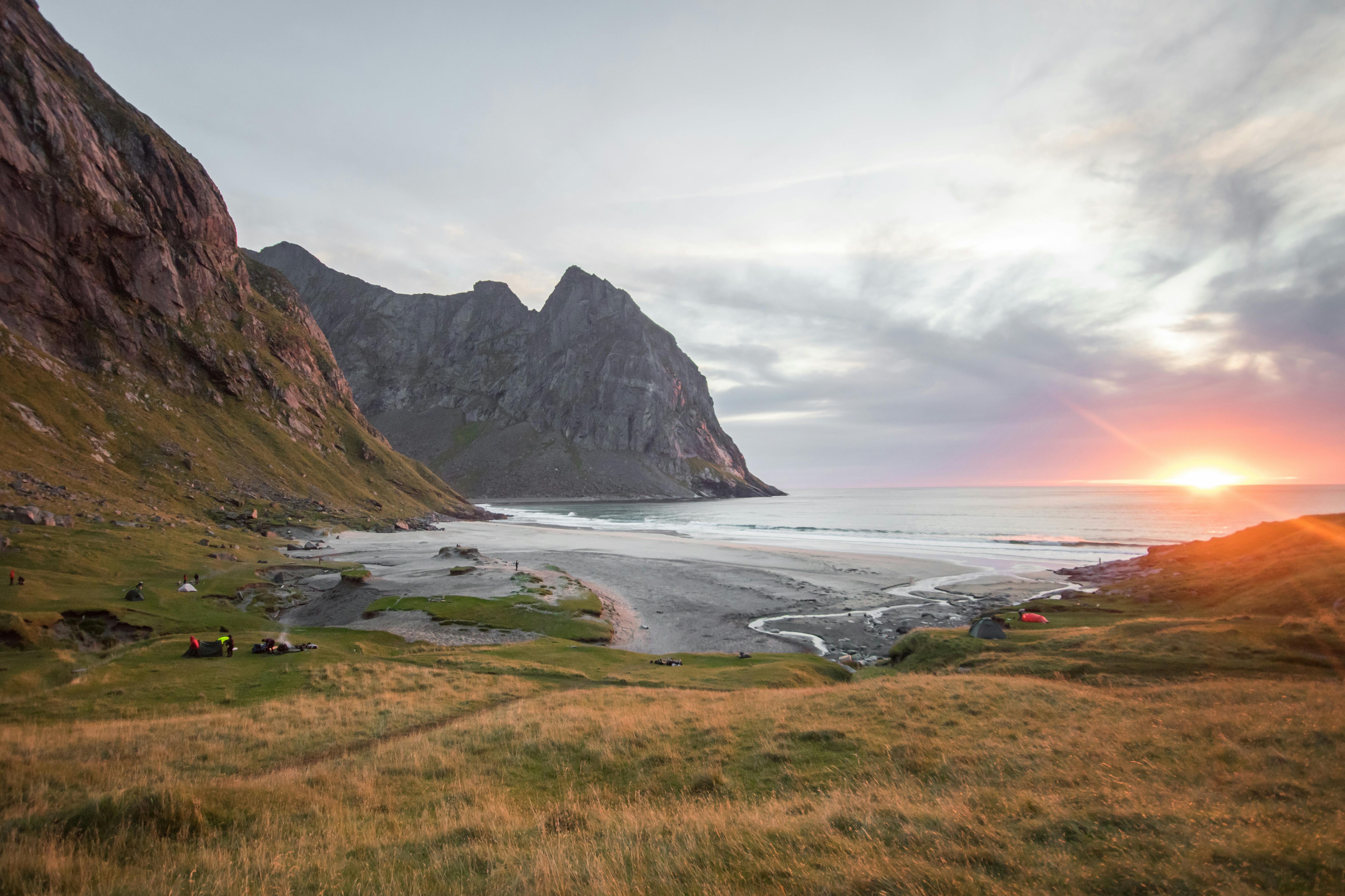 在高耸悬崖与海滩接壤之处，宁静的日落景色呈现出一派祥和、田园诗般的景观