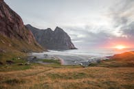 在高耸悬崖与海滩接壤之处，宁静的日落景色呈现出一派祥和、田园诗般的景观