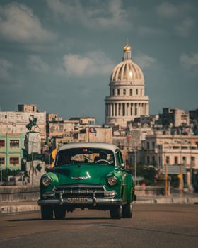 Capture the essence of Havana with a green vintage Chevrolet cruising past El Capitolio.