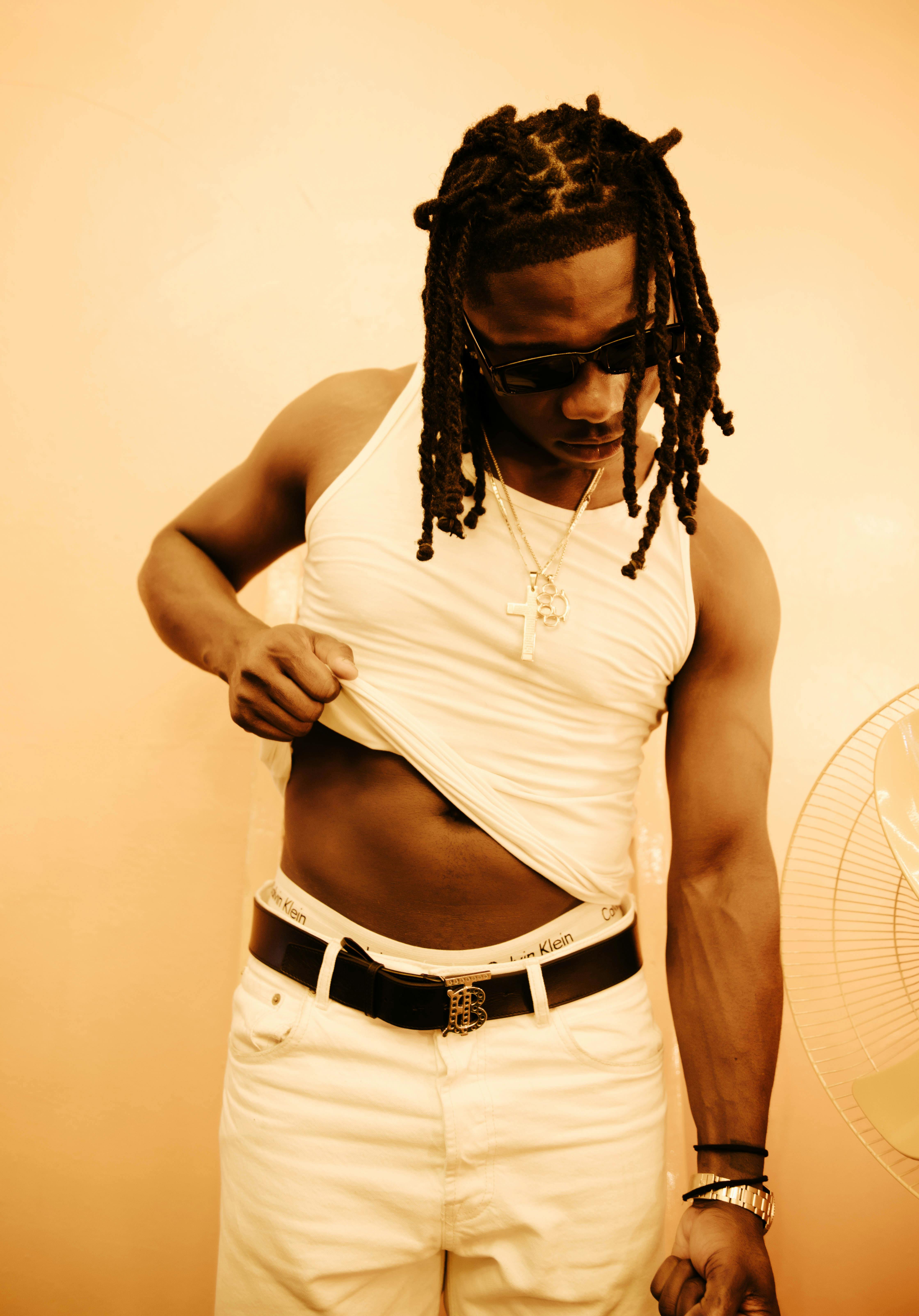 Fashionable portrait of a man in white clothing against a yellow background.